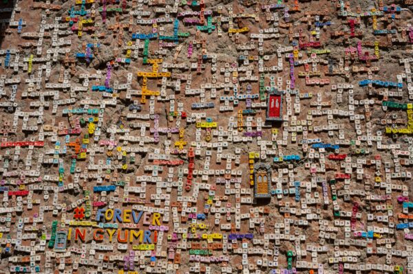 Vibrant tile mosaic on a wall showcasing letters and words in Gyumri, Armenia.