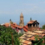 Charming town with historic bell tower and traditional rooftops under a clear sky.
