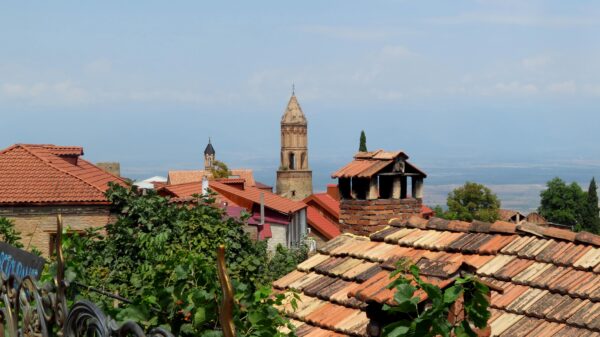 Charming town with historic bell tower and traditional rooftops under a clear sky.