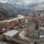 A stunning aerial shot of Mtskheta, Georgia, showcasing the historic Svetitskhoveli Cathedral and scenic landscapes.