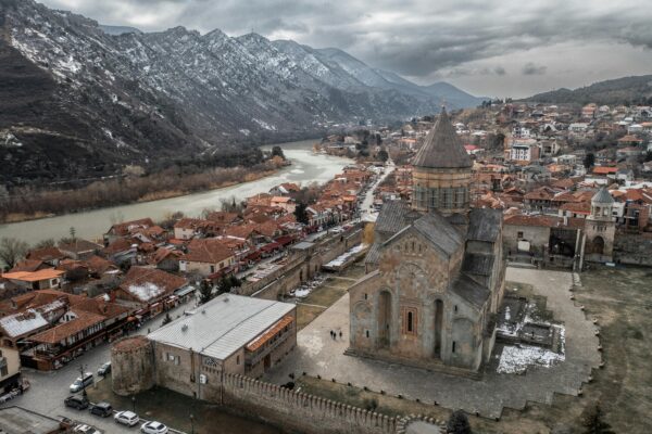 A stunning aerial shot of Mtskheta, Georgia, showcasing the historic Svetitskhoveli Cathedral and scenic landscapes.