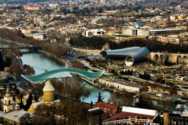 Stunning aerial shot of Tbilisi featuring the Bridge of Peace and modern architecture along the Kura River.