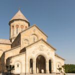 A beautiful historic stone church stands under a clear blue sky, representing architectural elegance.